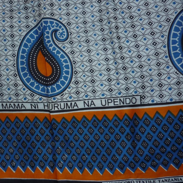 Das Foto zeigt einen weiß-blau-organge-gemusterten Kanga, ein Tuch, das in Ostafrika ein typisches Kleidungsstück ist.