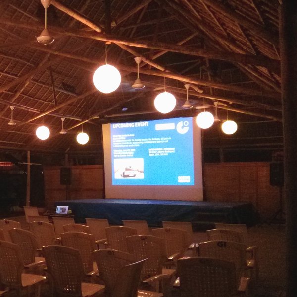 Das Foto zeigt das Freiluft-Kino des Goethe-Instituts Tansania in der Dunkelheit mit mehreren Reihen weißer Plastikstühle und einer Leinwand